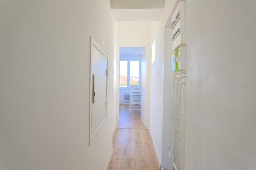 a hallway with white walls and a wooden floor at Appartement Calme - Arrière Gare - Parking Privée in Arras