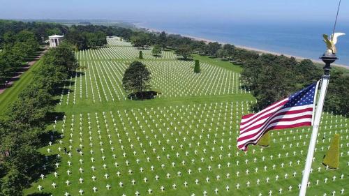 an american flag flying in front of a large cemetery at GITE A THEME D-DAY - situé à 15mn d'Omaha Beach - Animaux OK - Terrain clos - Aucuns voisins in Cartigny-lʼÉpinay