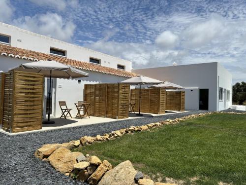 a house with a patio with umbrellas and a yard at Villa Lobos Tavira in Tavira