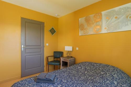 a bedroom with a bed and a door and a chair at Gîte Proche Mer 800 m in Plouézec