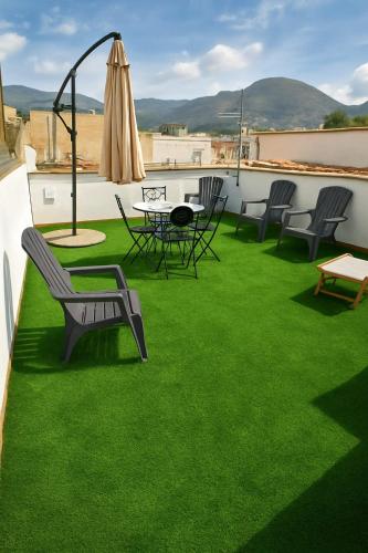 a patio with green grass and chairs and an umbrella at Appartamenti Penelope in Mondello