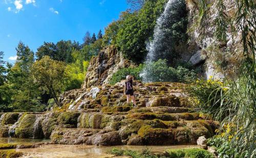 a person standing on the rocks in front of a waterfall at Paradis Provencal Le Calme total, Grande Piscine et Jacuzzi Chauffé, Salle de Jeux et Fresque du Nougat, Intimité in Montélimar