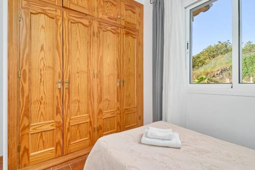 a bedroom with wooden cabinets and a bed with a window at Villa La Macera in Frigiliana