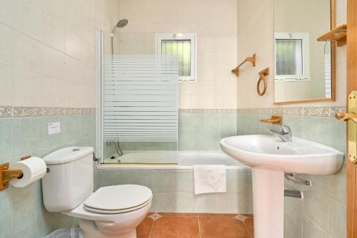 a bathroom with a toilet and a sink and a shower at Villa La Macera in Frigiliana