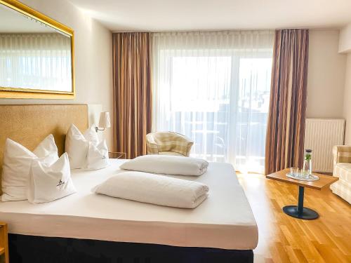 two beds in a hotel room with a large window at Hotel Malerhaus in Fügen