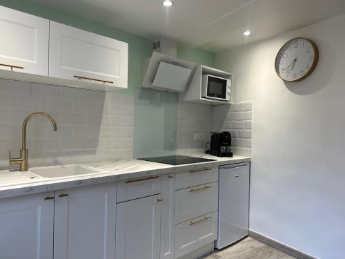 une cuisine avec des armoires blanches et une horloge au mur dans l'établissement Love room La Parenthèse Carnoules, à Carnoules
