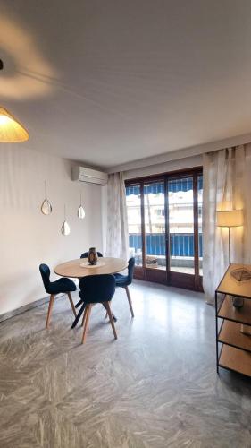 une salle à manger avec une table, des chaises et des fenêtres dans l'établissement Charmant 2 pièces proche plages parking priver, à Cagnes-sur-Mer