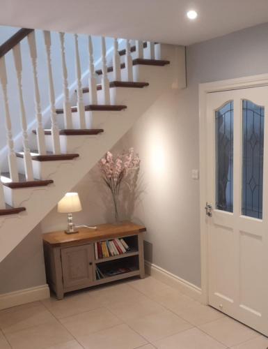 a hallway with a staircase with a table and a lamp at Home in Ballina, Ireland in Ballina