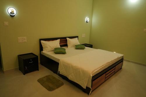 a bedroom with a large bed with two green pillows at The Calm County Homestay in Mānantoddy