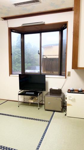 a living room with a tv and a large window at 日光いろは in Nikko