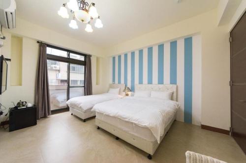 2 letti in una camera da letto con strisce blu e bianche di Iwaiker B&B a Città di Hualien
