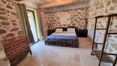 - une chambre avec un lit dans une pièce dotée de murs en pierre dans l'établissement Gitedeprovence le castelet, à La Motte