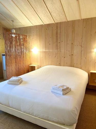 une chambre avec un lit blanc avec deux serviettes dessus dans l'établissement Le Cabanon du bord de mer, à Cayeux-sur-Mer