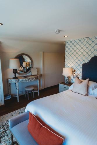 a bedroom with a bed and a desk with a mirror at Finch's Arms in Oakham