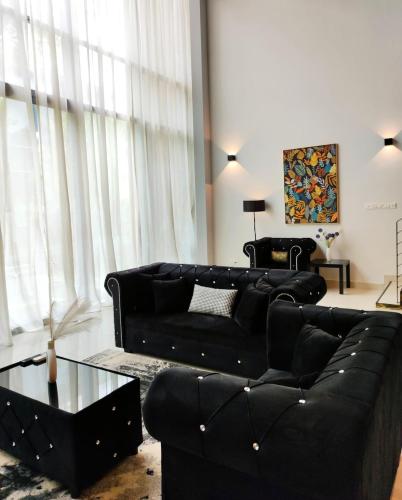 a living room with a black couch and a table at Cyberjaya Puchong JWJ Pool Villa in Cyberjaya