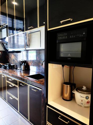 a kitchen with black cabinets and a black microwave at Cyberjaya Puchong JWJ Pool Villa in Cyberjaya