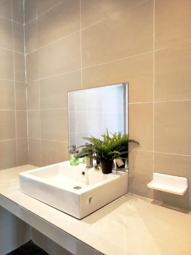 a bathroom sink with a mirror and a potted plant at Cyberjaya Puchong JWJ Pool Villa in Cyberjaya
