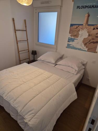 une chambre avec un grand lit blanc avec une fenêtre dans l'établissement Le Nid Bleu, à Perros-Guirec