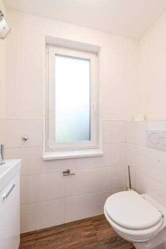 a white bathroom with a toilet and a window at StoderGarden Apartment - by myNests in Gröbming