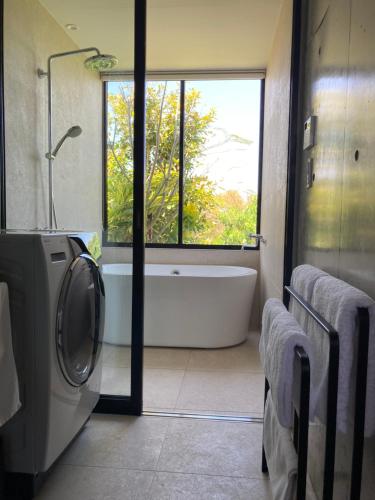 a bathroom with a tub and a washing machine at G.bouquet in Nakijin