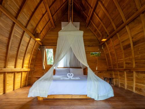 a bedroom with a bed in a wooden house at Aruna Jayanti Villa in Tejakula