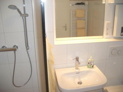 une salle de bain avec un lavabo et une douche avec un miroir dans l'établissement Wellness-Appartement, à Westerland