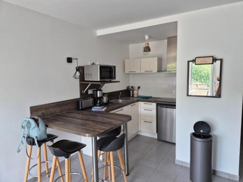 - une cuisine avec une table et des tabourets en bois dans l'établissement Le Nid Bleu, à Perros-Guirec