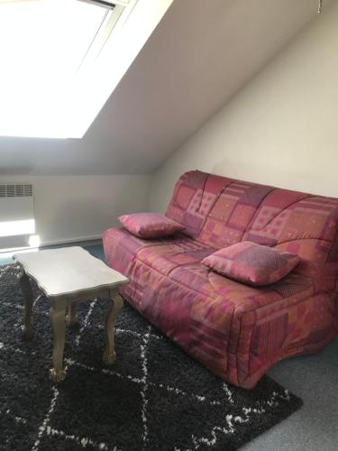 un salon avec un canapé rose et une table dans l'établissement Duplex, à La Celle-sous-Gouzon