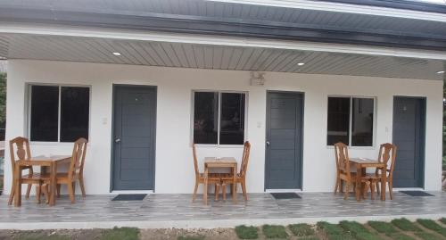 a porch with four chairs and a table and windows at Sebastian Guest House in Moalboal