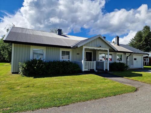 a white house with a porch on a yard at Fisherman's house-rooms 1-8 persons near Storuman in Stensele