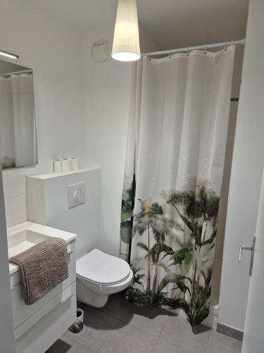 une salle de bain avec toilettes et rideau de douche dans l'établissement Le Nid Bleu, à Perros-Guirec