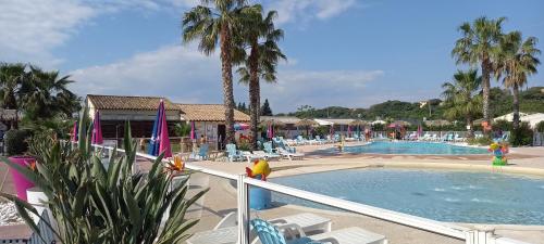 - une piscine dans un complexe avec des chaises et des palmiers dans l'établissement Azur072, à Fréjus
