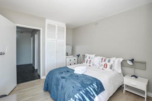 a white bedroom with a bed with a blue blanket at Voetjieshang in Yzerfontein