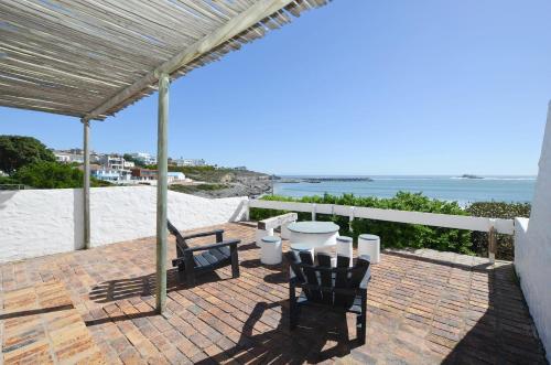 a patio with chairs and a table and the ocean at Voetjieshang in Yzerfontein