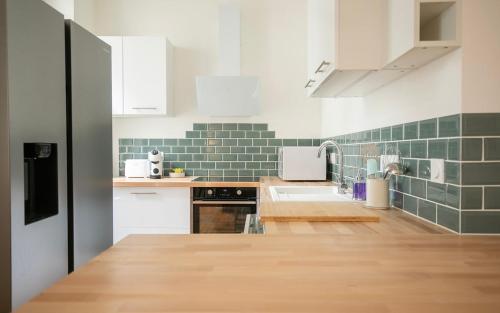 - une cuisine avec du carrelage vert et blanc sur le mur dans l'établissement Le Gare Nord T3 de Haut Standing Cosy et Relaxant, à Nantes