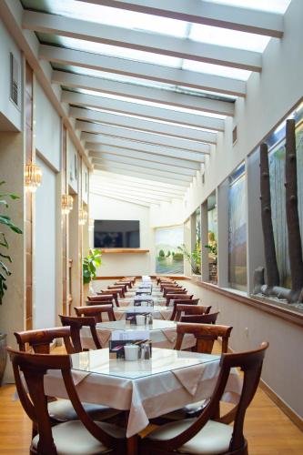 Un comedor largo con una mesa larga y sillas. en Elena Hotel, en Kozani