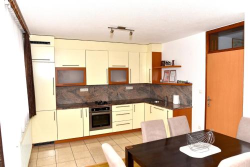 a kitchen with white cabinets and a table with chairs at Sutjeska in Modriča