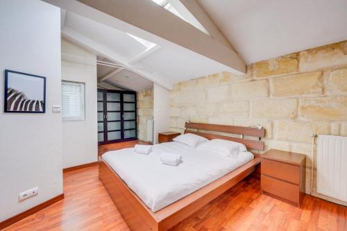 une chambre avec un grand lit dans un mur de briques dans l'établissement Spacious, quiet flat in the heart of Bordeaux, à Bordeaux