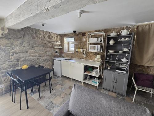 a kitchen with a table and a stone wall at CASITA RECIEN HABILITADA A ESTRENAR CON PISCINA EN MALVAS Tuy in Malvas