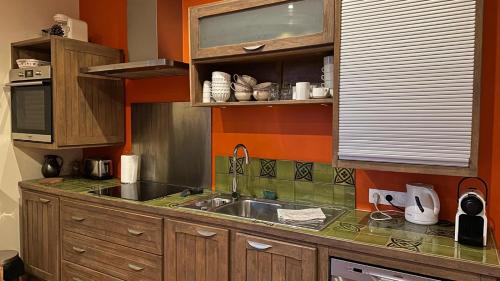 - une cuisine avec un évier et un mur orange dans l'établissement L'Appartement d'Egard 8 personnes Normandie, à Tamerville