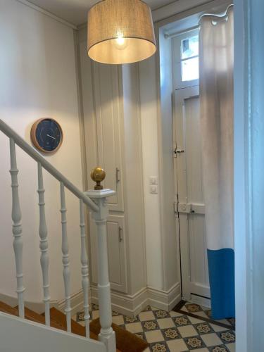 un couloir avec un escalier avec une horloge et une porte dans l'établissement Villa Les Abeilles - Wimereusienne, à Wimereux