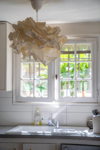 une cuisine avec un évier et deux fenêtres dans l'établissement Villa - Piscine partagée dans résidence privée - Proche Cannes, à Mougins