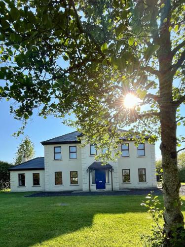 a large white house with the sun shining on it at Countryside House & private garden in Limerick