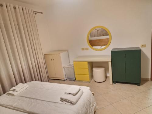 ein Schlafzimmer mit einem Bett, einem Schreibtisch und einem Spiegel in der Unterkunft Beachfront Apartment in Sarandë