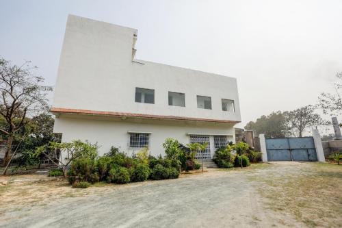 een wit huis met struiken ervoor bij Super Hotel O The Nirvana Resorts in Dhanbad