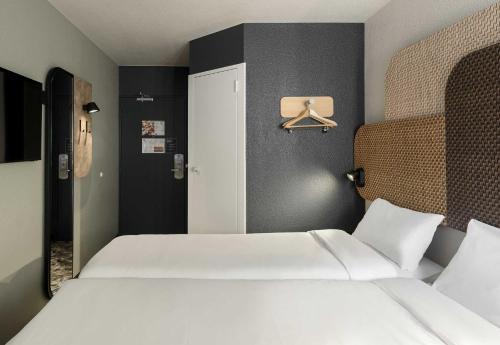 a bedroom with two white beds and a door at B&B HOTEL Toulouse Cité de l'Espace Hurel in Toulouse