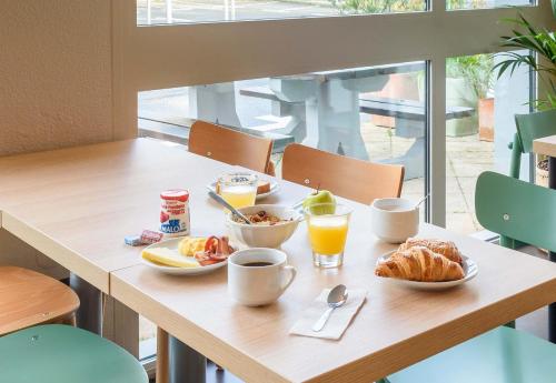 a table with breakfast foods and drinks on it at B&B HOTEL Toulouse Cité de l'Espace Hurel in Toulouse