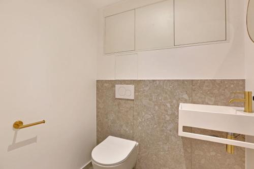 une salle de bain blanche avec des toilettes et un lavabo dans l'établissement Welcoming & charming apartment - 1BR 4P - Palais-R, à Paris