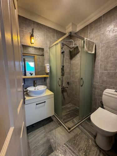 a bathroom with a shower and a sink and a toilet at Ergül Motel in Kucukkuyu