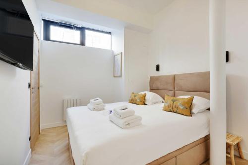 une chambre avec un lit blanc avec des serviettes dessus dans l'établissement Superbe appartement - 2BR-6P - Bastille, à Paris